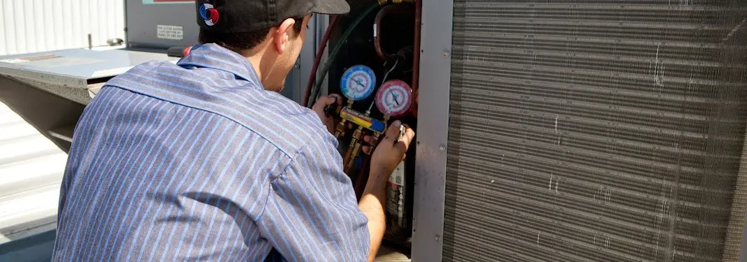 HVAC technician servicing a condenser unit in Sultan
